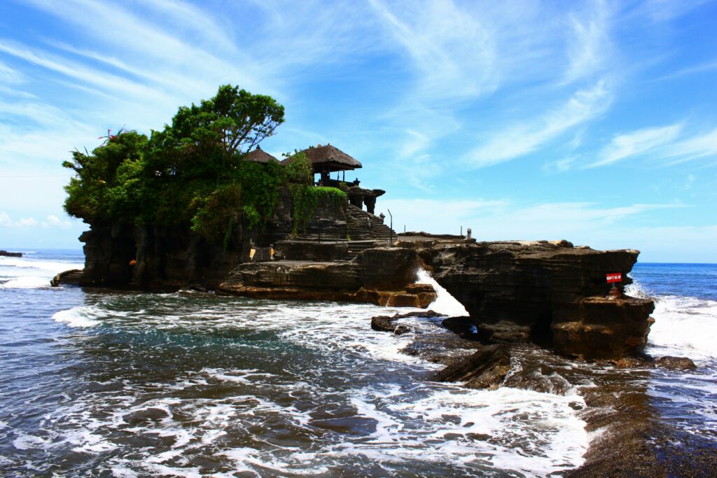 Stunning image of Tanah Lot Temple on a sunny day in Bali, showcasing its iconic coastal setting.