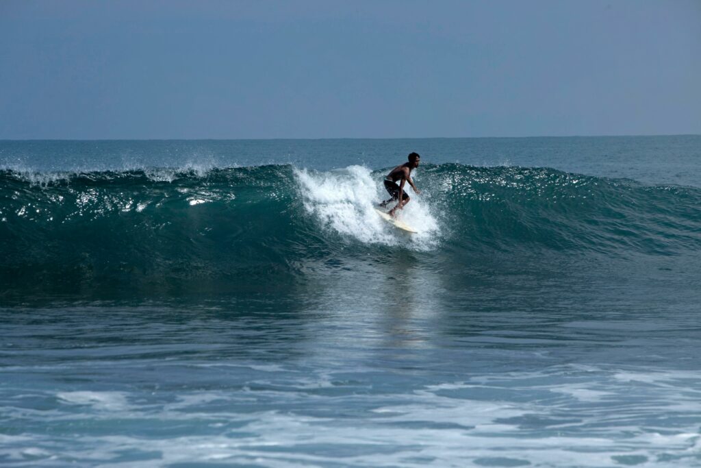 A surfer skillfully navigating a wave on a sunny beach day, showcasing adventure sports.